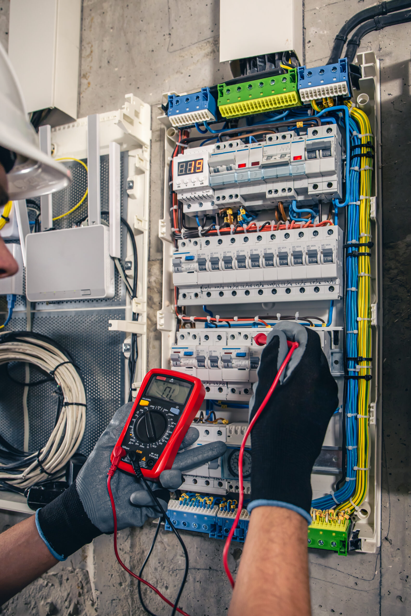 Man, an electrical technician working in a switchboard with fuses. Installation and connection of electrical equipment. Professional uses a tablet. Image by pvproductions on Freepik